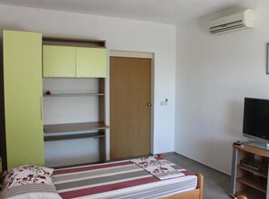 Una camera da letto con un letto, una TV, un armadio e una porta.