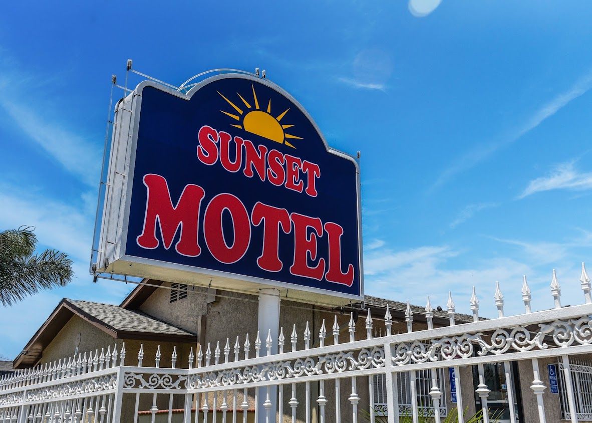 A motel sign with a sun graphic and the name 'Sunset Motel' in bold letters.