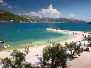 A beach with clear turquoise water, a sandy shore, and a few people enjoying the water. - Two Bedroom with Balcony (A3) (Marina)