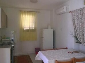 A small kitchenette with a refrigerator, a sink, and a window with curtains. There is a table with chairs and a rug on the floor. - Three Bedroom Apartment with Terrace (A2) (Marina)
