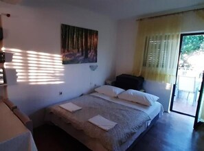 Een slaapkamer met een bed, een schilderij aan de muur en een raam met gordijnen.