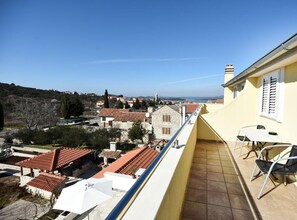 A balcony with a view of a coastal town, a tiled floor, and a table with chairs. - One Bedroom Apartment with Balcony and Sea View-ŽUTI (Murter)