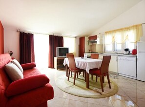 Ein kompakter Wohnraum mit Essbereich, Küchenzeile und einem roten Sofa.