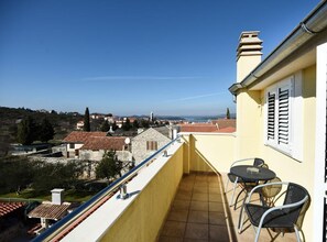 A balcony with a view of a town, a table, and two chairs. - Standard One Bedroom Apartment with Balcony and Sea View-CRVENI (Murter)