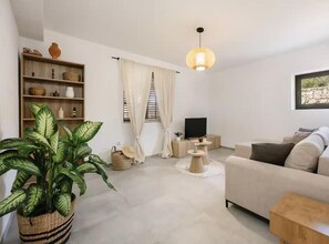 A living room with a sofa, a television, a plant, and a bookshelf. - Five Bedroom Apartment with Sea View (National Park Kornati)