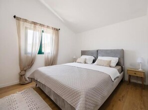 Ein Schlafzimmer mit Bett, Vorhängen, Nachttisch und Lampe.