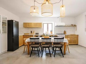 A modern kitchen with a dining area, featuring a black refrigerator, wooden cabinets, and a central island with chairs. - Five Bedroom Apartment with Sea View (National Park Kornati)