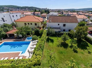 A residential area with a swimming pool, a well-maintained lawn, and a view of the surrounding neighborhood. - Two Bedroom Apartment with Balcony and Garden View (Trogir)