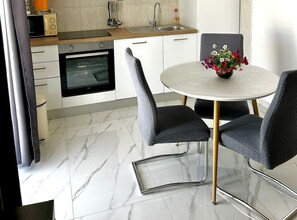 A modern kitchen with a built-in oven, a dining table with chairs, and a flower vase. - One Bedroom Apartment with Balcony and City View 2 (Trogir)