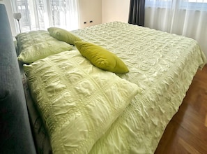 A bed with a textured green bedspread and a single yellow pillow. - Two Bedroom Apartment with Balcony and Garden View (Trogir)