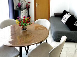 Uma sala de jantar com uma mesa redonda, cadeiras e um vaso de flores.