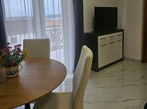 Quarto de hotel com uma mesa de jantar, cadeiras, uma televisão em um móvel e vista pela janela.