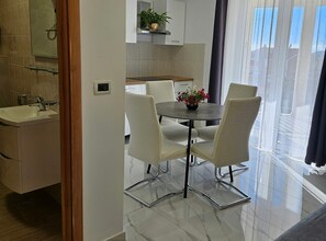 A modern kitchen with a dining area featuring a glass table and chairs. - One Bedroom Apartment with Balcony (Trogir)