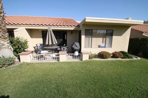 A single-story house with a patio, a covered seating area, and a visible garage door. - Grab a glass of wine and enjoy the Lake Views! (Palm Desert)