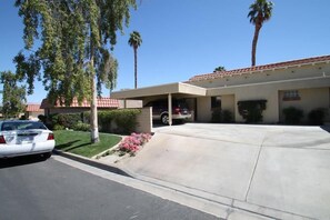 A residential building with a driveway, parked cars, and a palm tree. - Grab a glass of wine and enjoy the Lake Views! (Palm Desert)