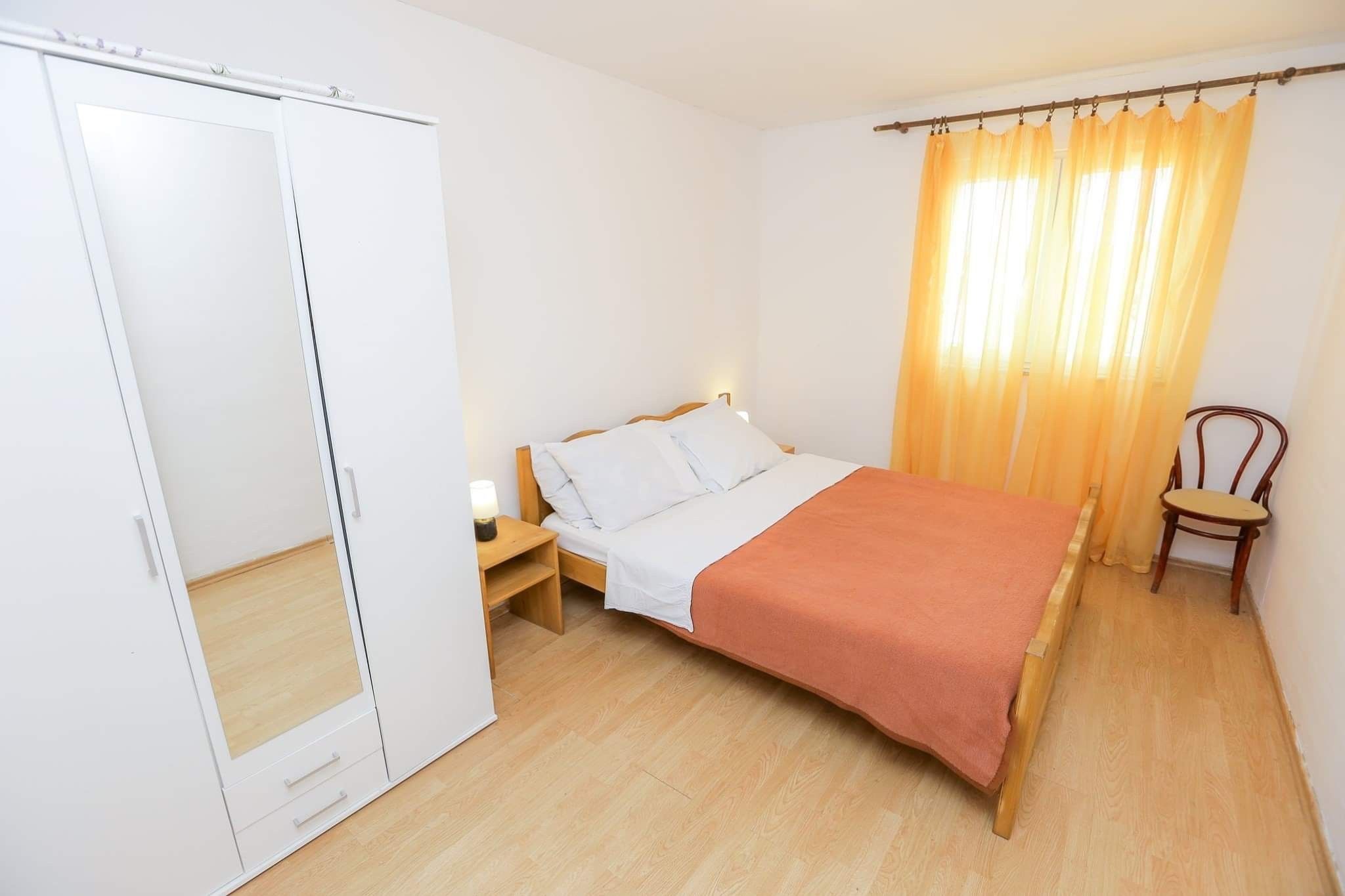 A bedroom with a bed, nightstand, wardrobe, and a chair.