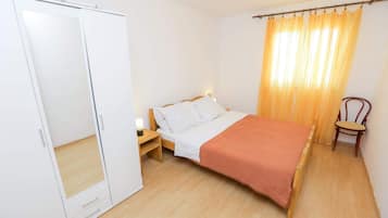 A bedroom with a bed, nightstand, wardrobe, and a chair.