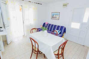 A dining area with a table, chairs, a sofa, and a potted plant. - Apartment 'Panorama' with Sea View, Wi-Fi and Air Conditioning (Pakoštane)