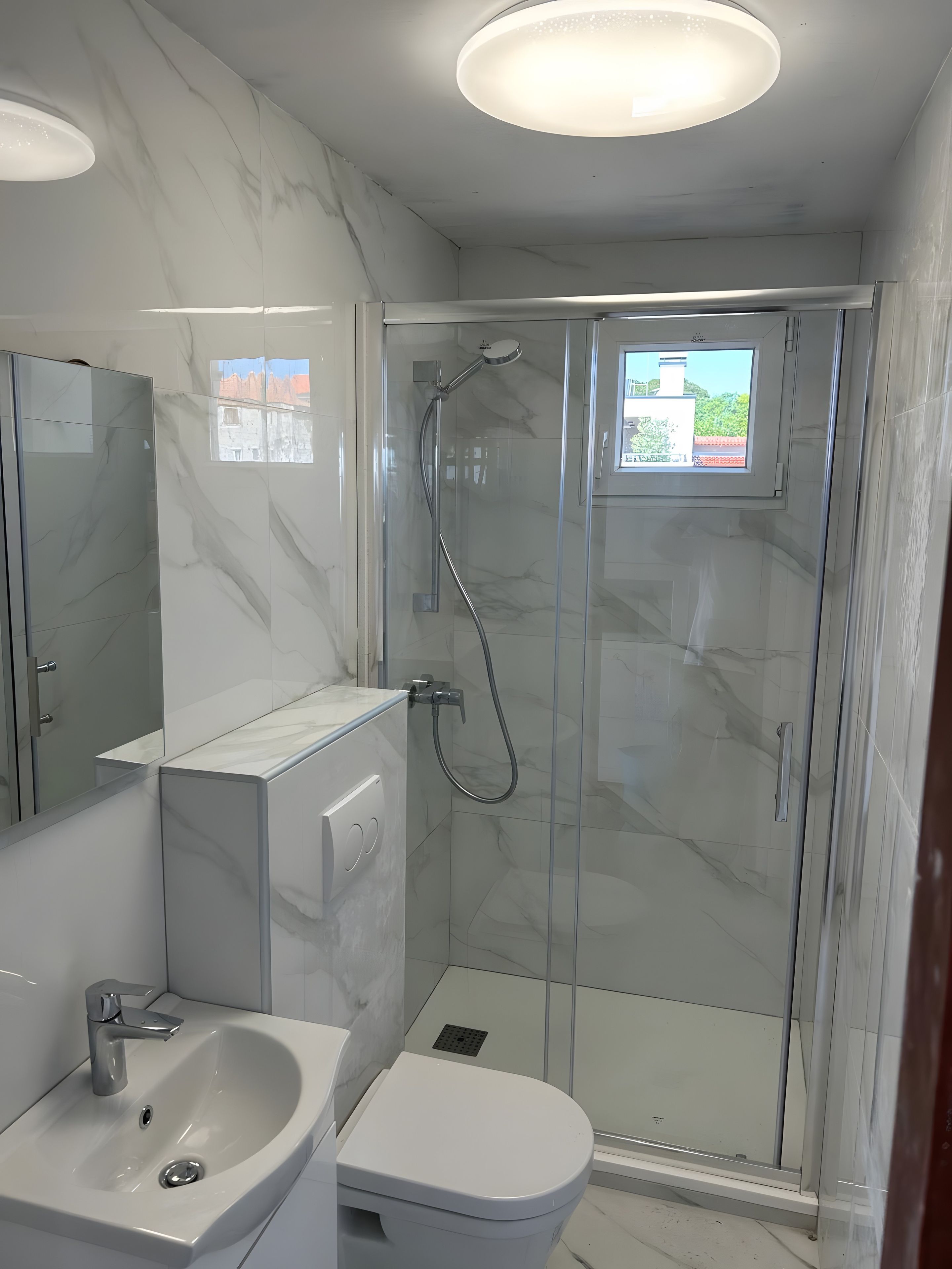 A modern bathroom with a glass-enclosed shower, a white sink, and a toilet.