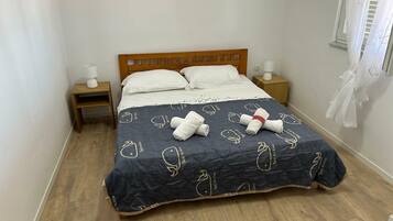 A bed with a dark blue blanket featuring white patterns, two white pillows, and two bedside lamps on wooden nightstands.