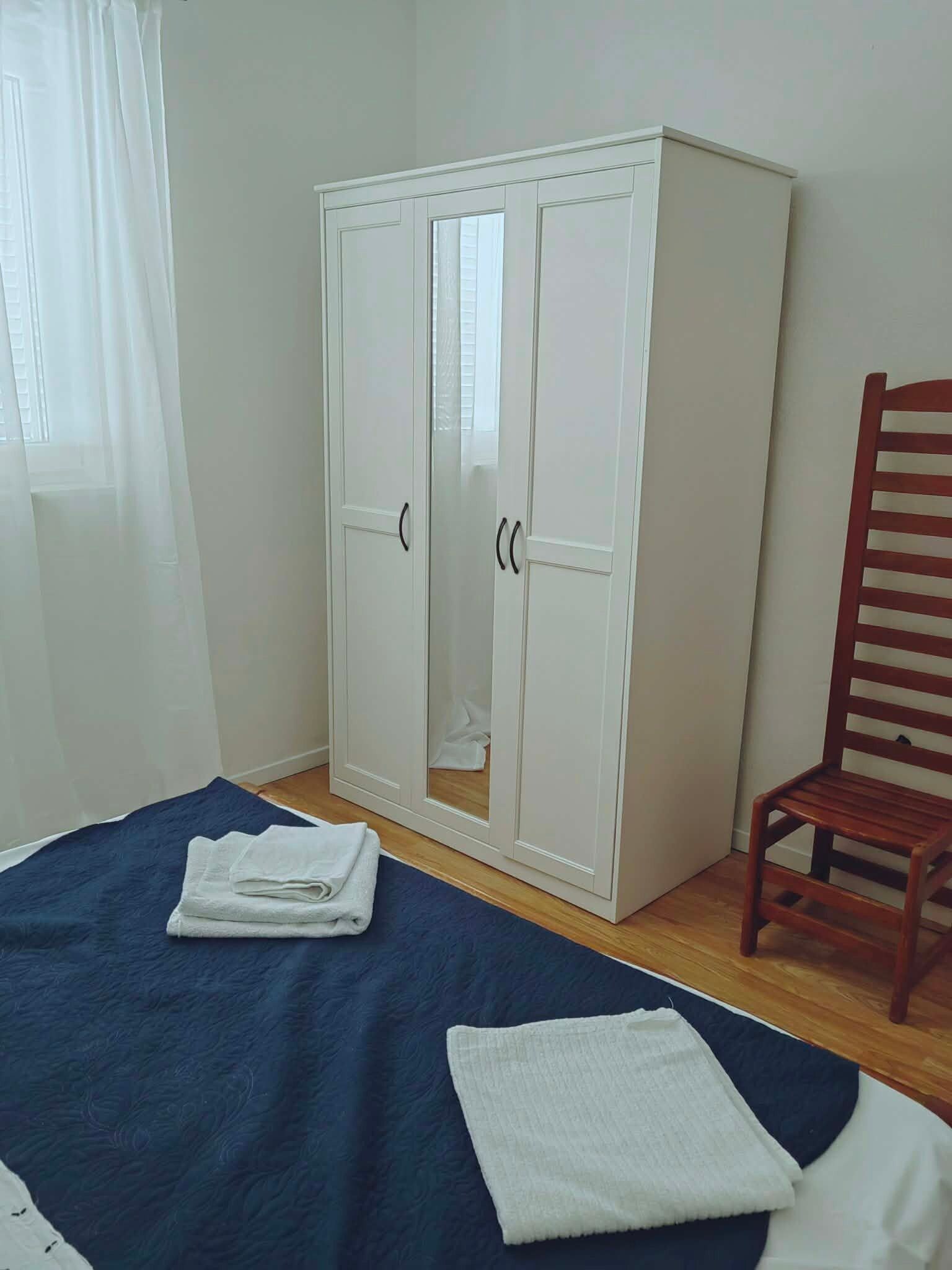 A bedroom with a bed, a wardrobe, and a chair.