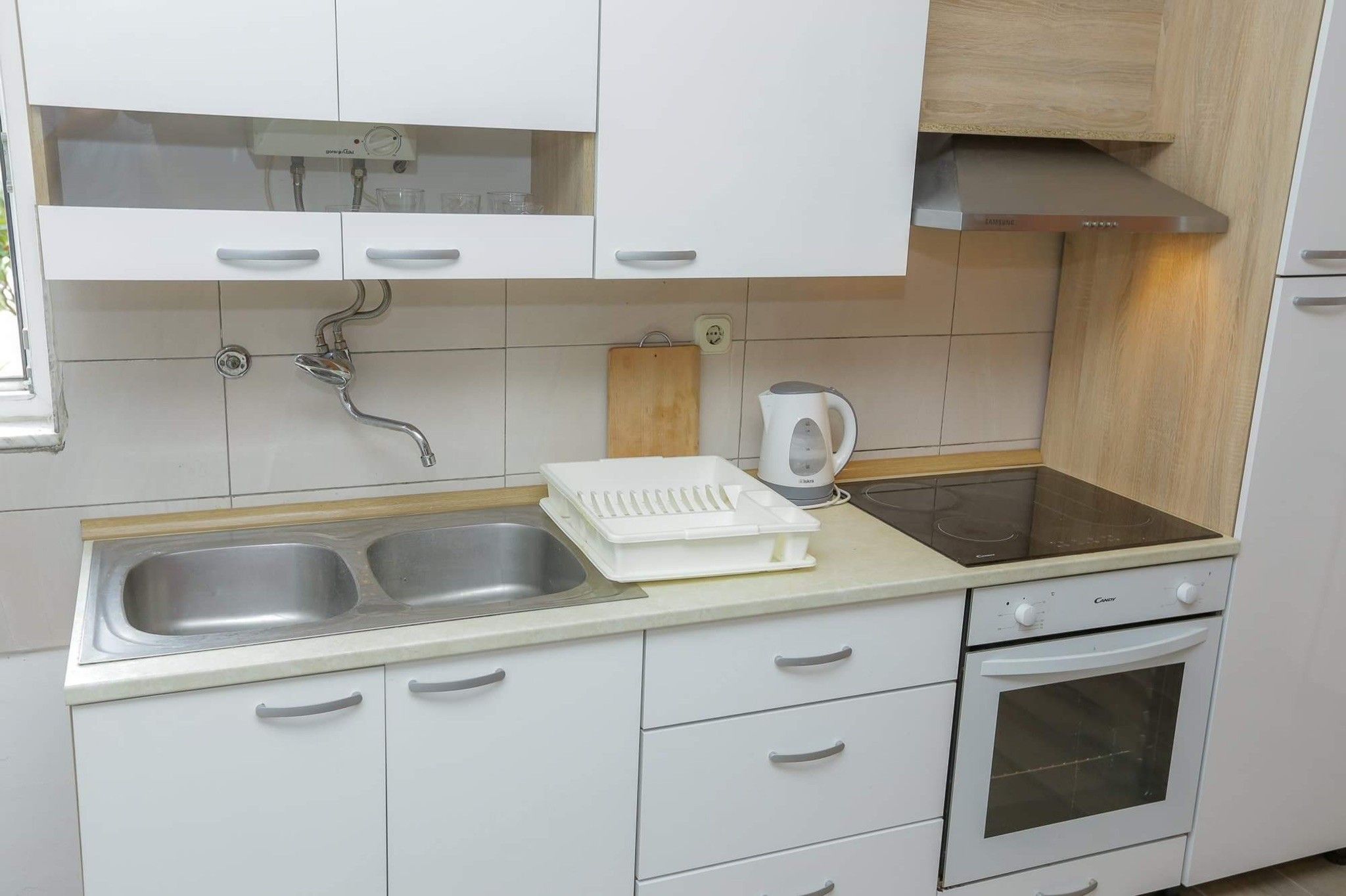 Una kitchenette con un lavamanos doble, un hervidor y un horno empotrado.