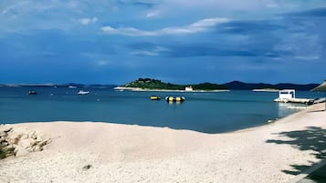 Uma praia de pedras com vista clara para o mar e terra ao longe.