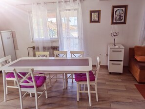 A dining area with a white table and chairs, a white cabinet, and a framed picture on the wall. - Apartment 'Family Apartments' with Sea View, Wi-Fi and Air Conditioning (Pakoštane)