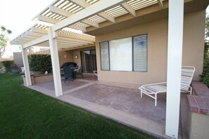 A covered patio area with a grill, seating, and a view of the street. - Great Views and Palm Desert Flare! (Palm Desert)