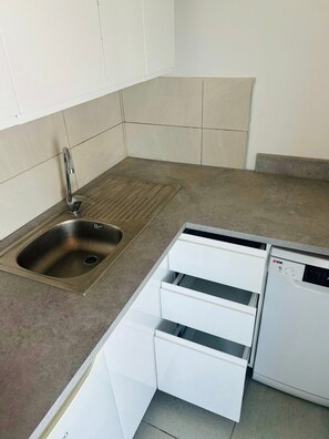 A kitchen with a stainless steel sink, a dishwasher, and white cabinetry. - Apartment 'Mediterranean' with Sea View, Wi-Fi and Air Conditioning (Pakoštane)
