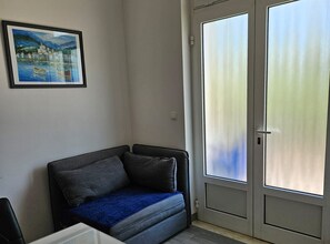 A room with a sofa, a door with frosted glass panels, and a framed painting on the wall. - Two Bedroom Apartment in ground floor (Trogir)