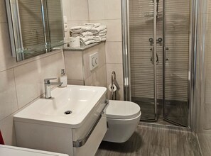 A modern bathroom with a white sink, toilet, and glass shower enclosure. - Two Bedroom Apartment in ground floor (Trogir)
