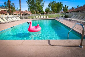A swimming pool with a pink flamingo float, surrounded by lounge chairs and a white fence. - Lake Views and Plenty of Room for All! (Palm Desert)