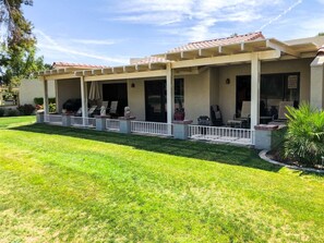 A covered outdoor patio with seating, a grill, and a fenced area. - Enjoy the Outdoors on the 16th Fairway! (Palm Desert)