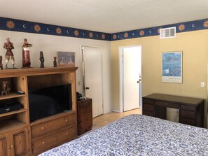 Une chambre à coucher comprenant un lit, une commode en bois, une télévision et des objets de décoration.