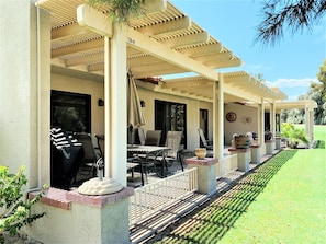 A covered outdoor seating area with tables and chairs, a barbecue grill, and a well-maintained lawn. - Enjoy the Outdoors on the 16th Fairway! (Palm Desert)