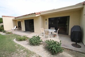 Eine Terrasse mit Tisch und Stühlen, ein Grill und ein überdachter Bereich.