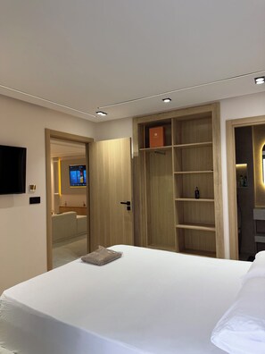 Ein modernes Hotelzimmer mit einem Bett, einem Fernseher, einem Holzschrank und einer eingebauten Regaleinheit.