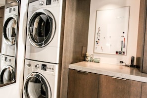 A laundry room with multiple washing machines, a control panel, and a mirror. - Beautiful and Spacious El Paseo Pool Home (Palm Desert)