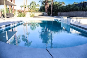 A swimming pool with clear water, surrounded by a tiled deck and palm trees. - Beautiful and Spacious El Paseo Pool Home (Palm Desert)