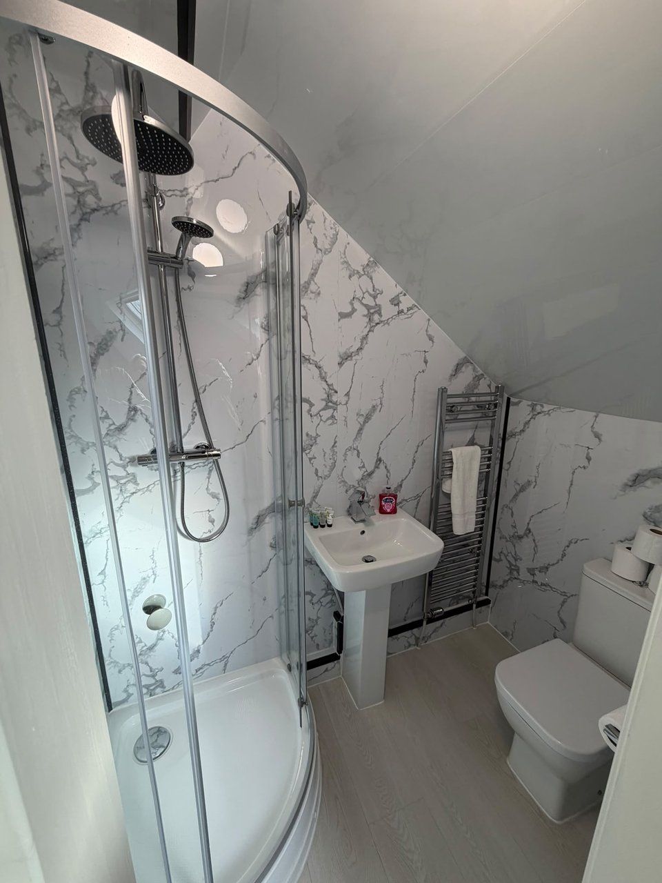 A bathroom with a glass-enclosed shower, a white sink, and a toilet.