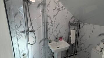 A bathroom with a glass-enclosed shower, a white sink, and a toilet.