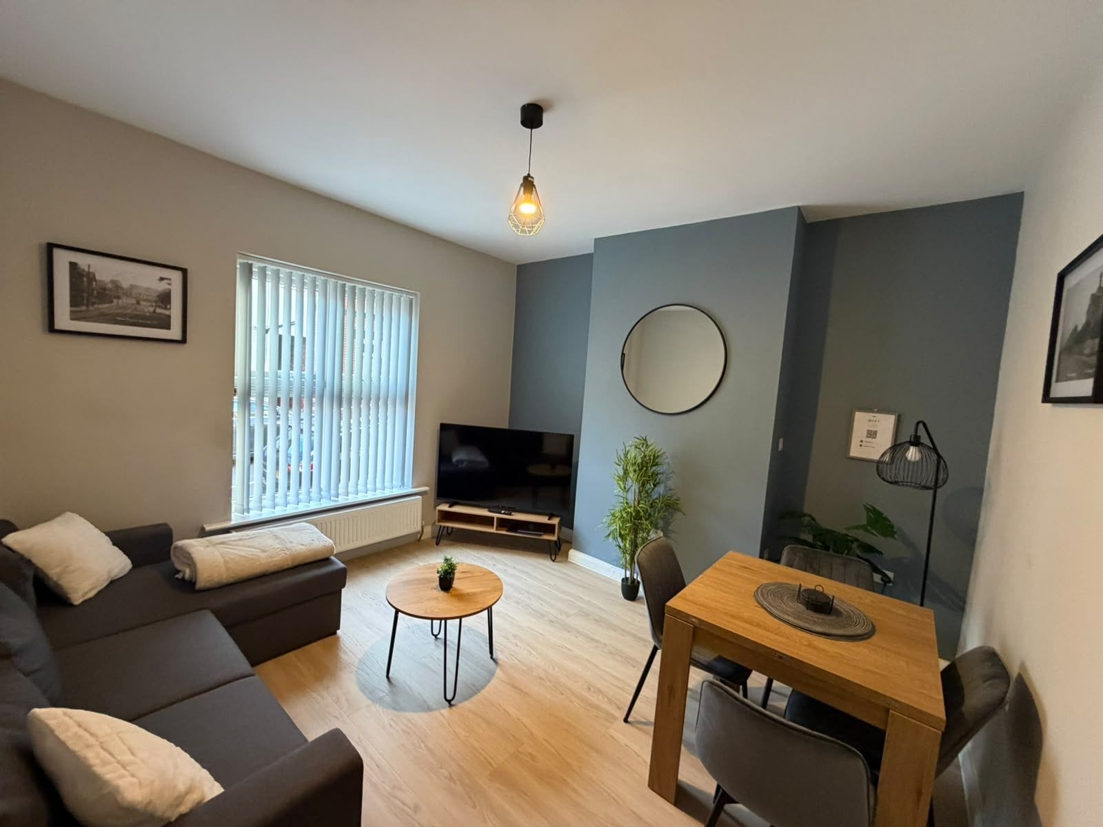 Una sala de estar moderna con un sofá, una mesita redonda, un televisor y una mesa de comedor.