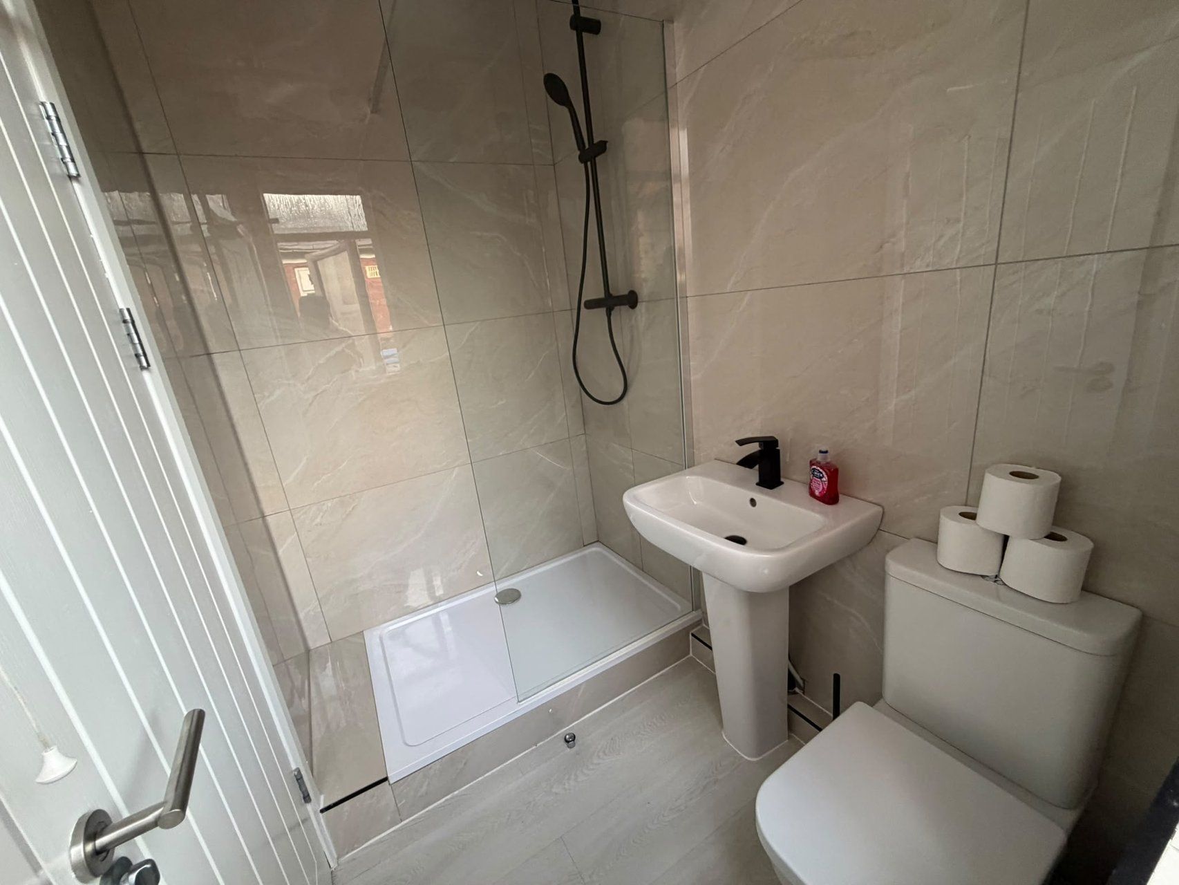 Un baño moderno con ducha, lavamanos e inodoro.