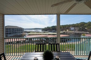Ein Balkon mit Blick auf einen Fluss, ein Gebäude gegenüber und eine Grünfläche.