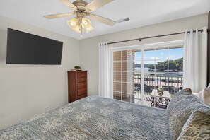 Quarto com cama, cômoda, ventoinha no teto, janela com vista para uma varanda e porta.
