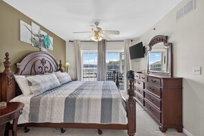 Ein Schlafzimmer mit Bett, Kommode, Deckenventilator und Blick ins Freie.