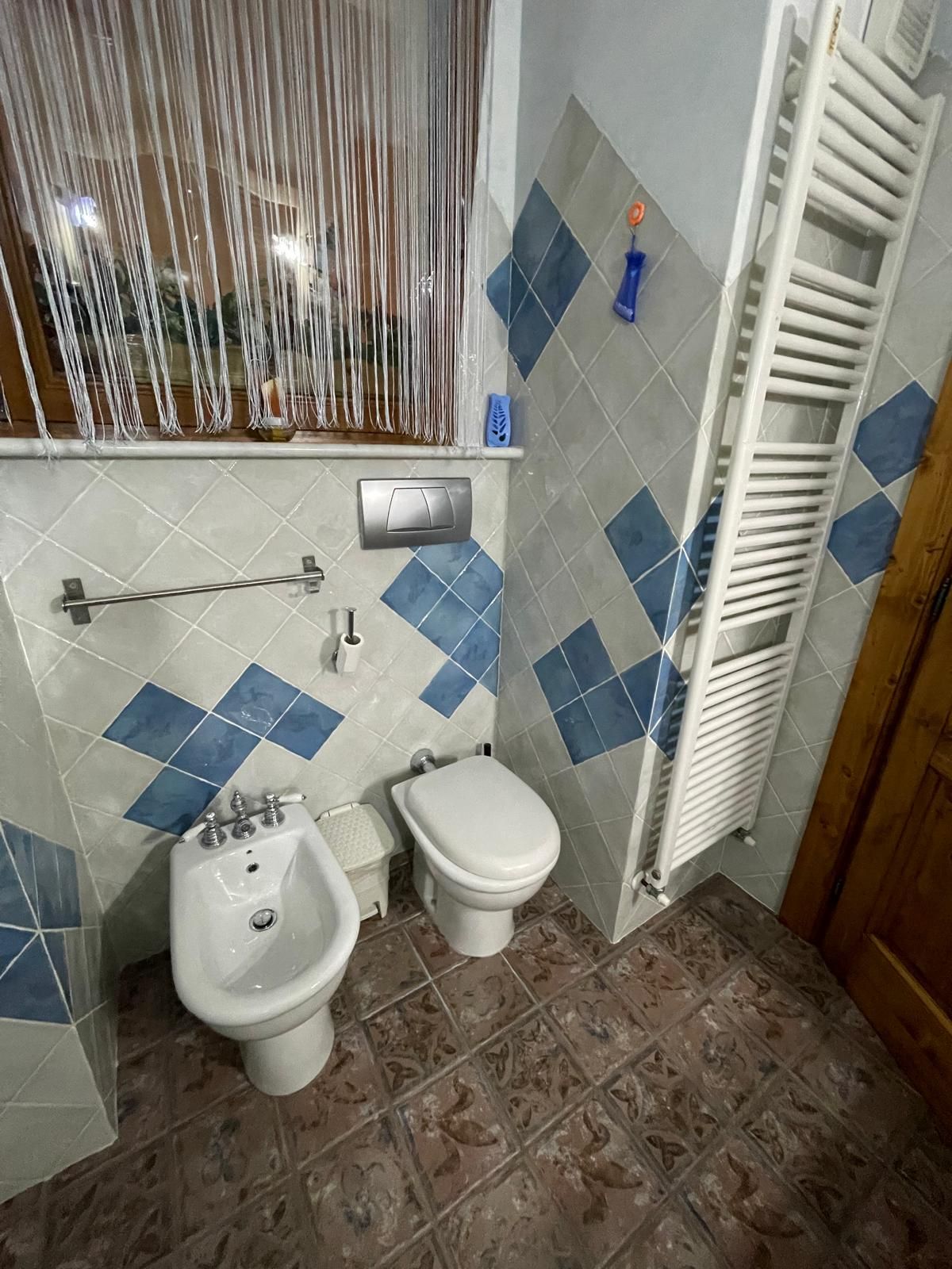 Un bagno con servizi igienici, bidet e lavandino, pavimento piastrellato e porta asciugamani.