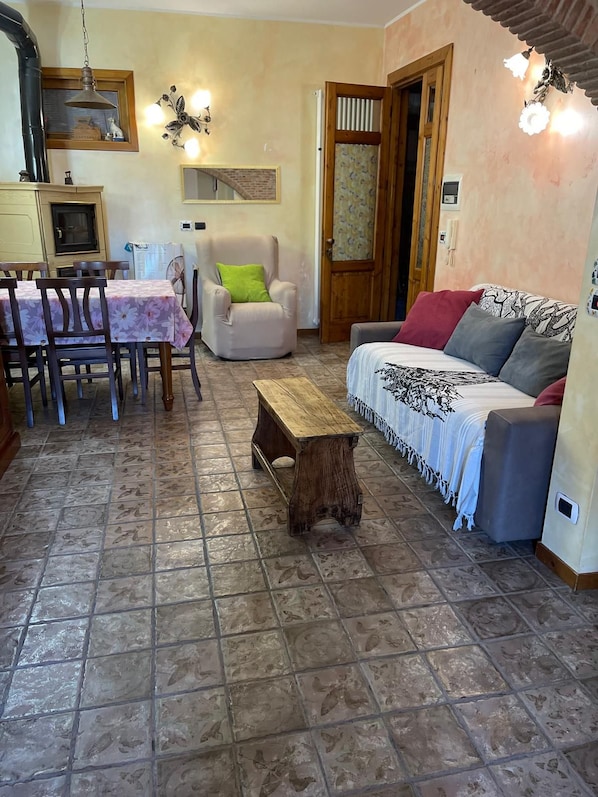A living room with a sofa, a dining table with chairs, a wooden coffee table, and a fireplace.