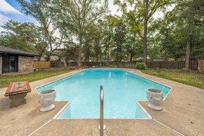 A rectangular swimming pool with a metal ladder in the center, surrounded by a concrete deck. - Pet Friendly Home with Private Pool, Home Gym, Ping Pong Table & Wifi (Fort Walton Beach)